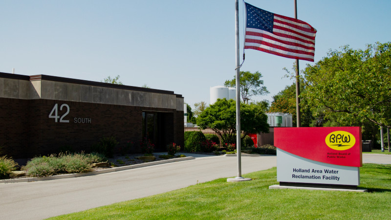 Holland Water Reclamation Facility front of the building on a sunny day with the American flag at half mast.