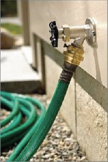 Grey outdoor hose spigot with a hose ribb vacuum breaker attached just below the knob.