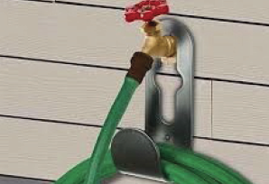 Green outdoor hose spigot attached to beige siding