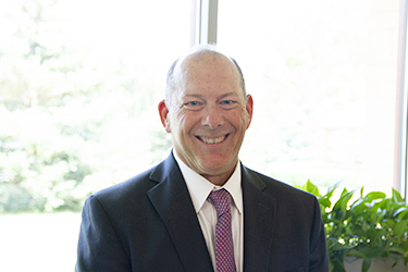 male executive wearing a black suit coat, white shirt and red tie