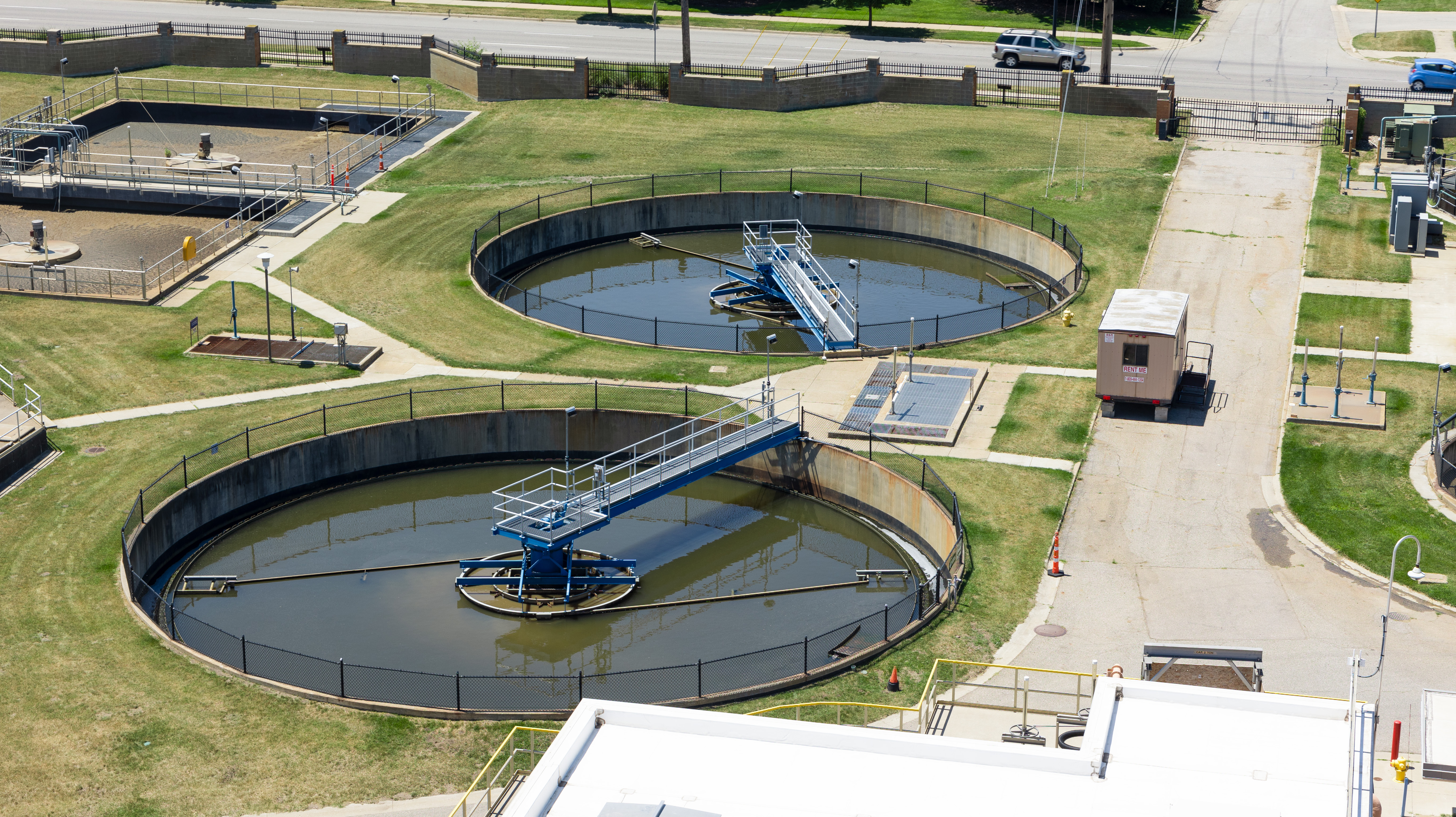 Water reclamation tanks with skimming arms and green grass between tanks