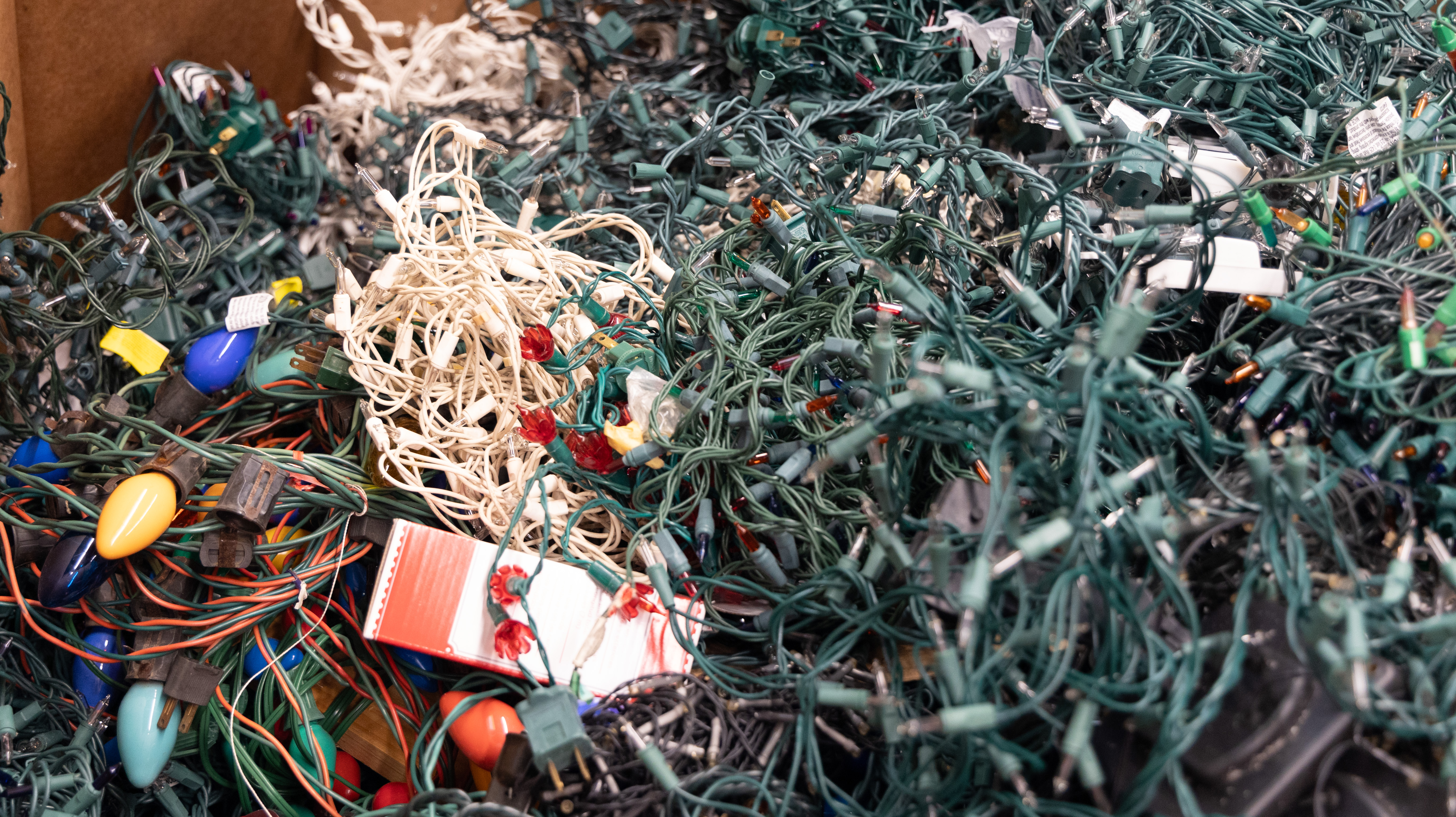 Cardboard bin filled with colorful holiday lights to be recycled.