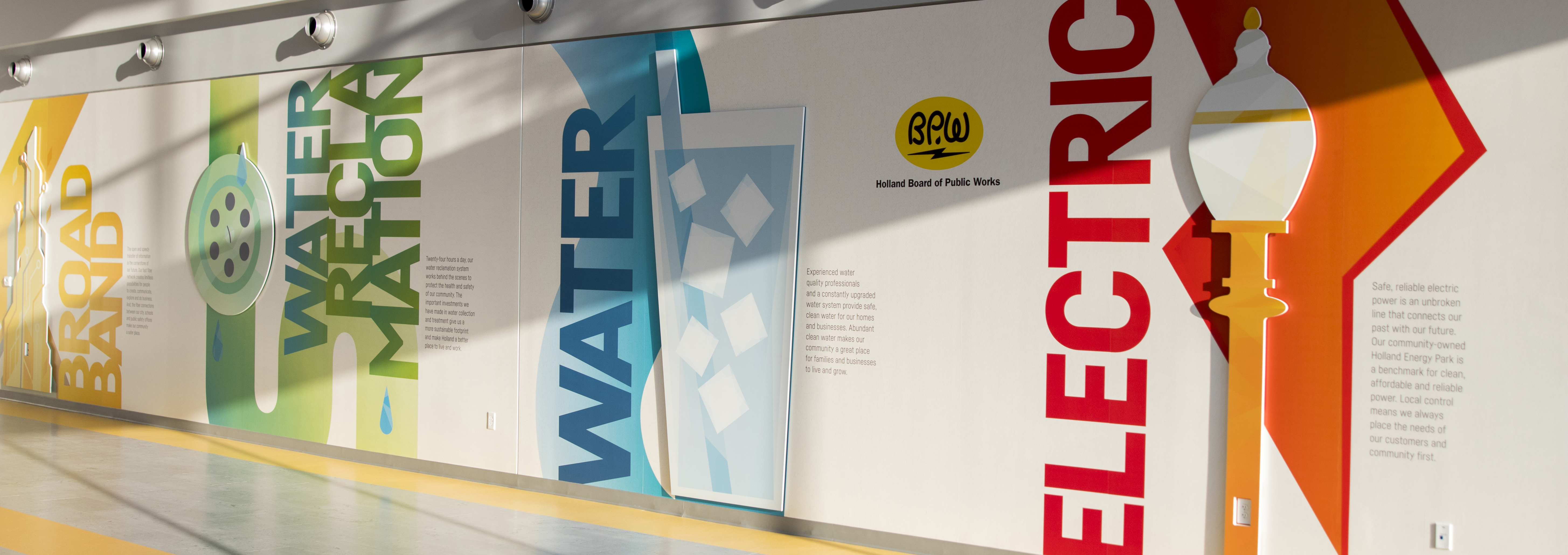 wall inside of a building with artwork that says electric, water, water reclamation, and broadband