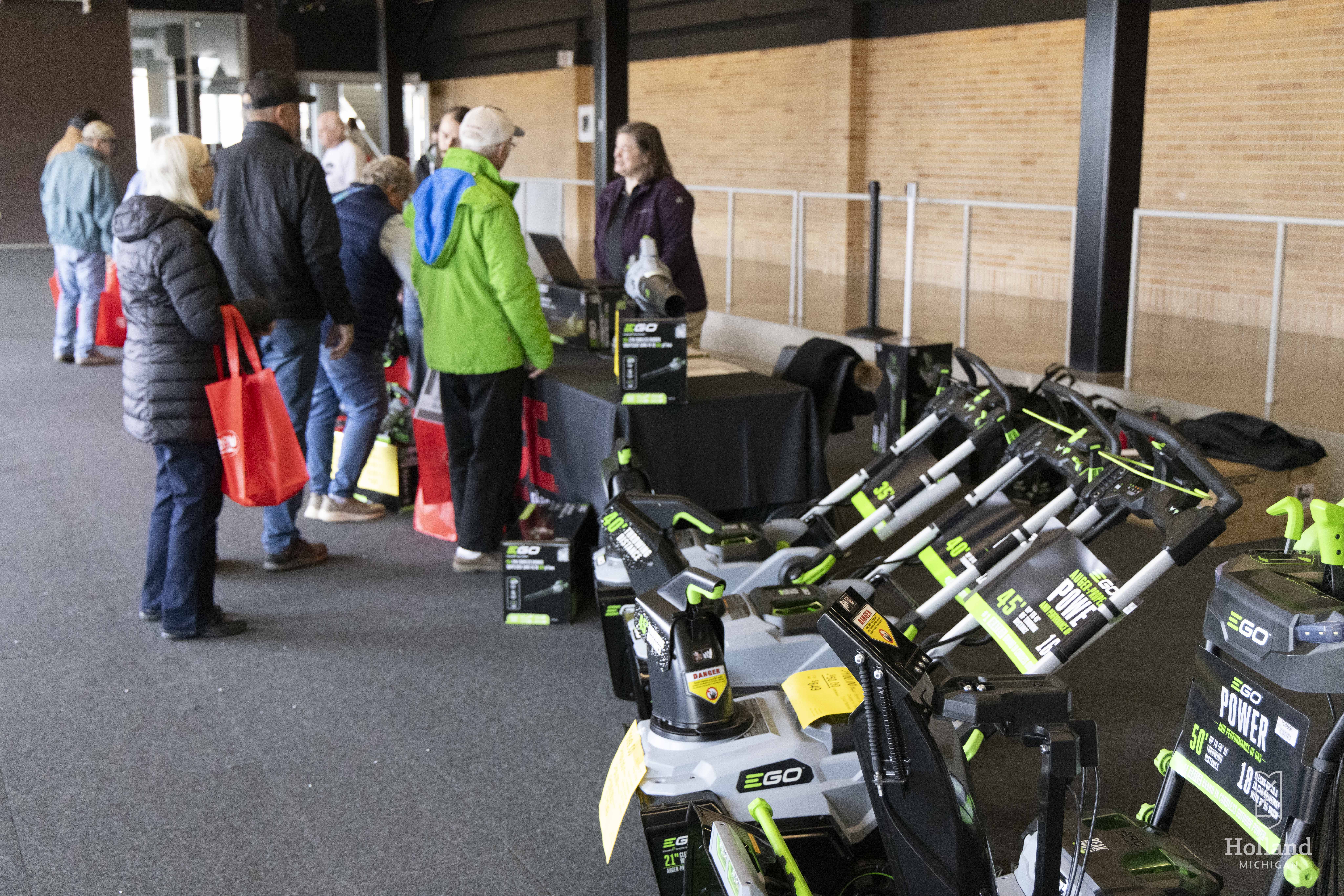 Visser Ace employees stand behind EGO snowblowers under an awning