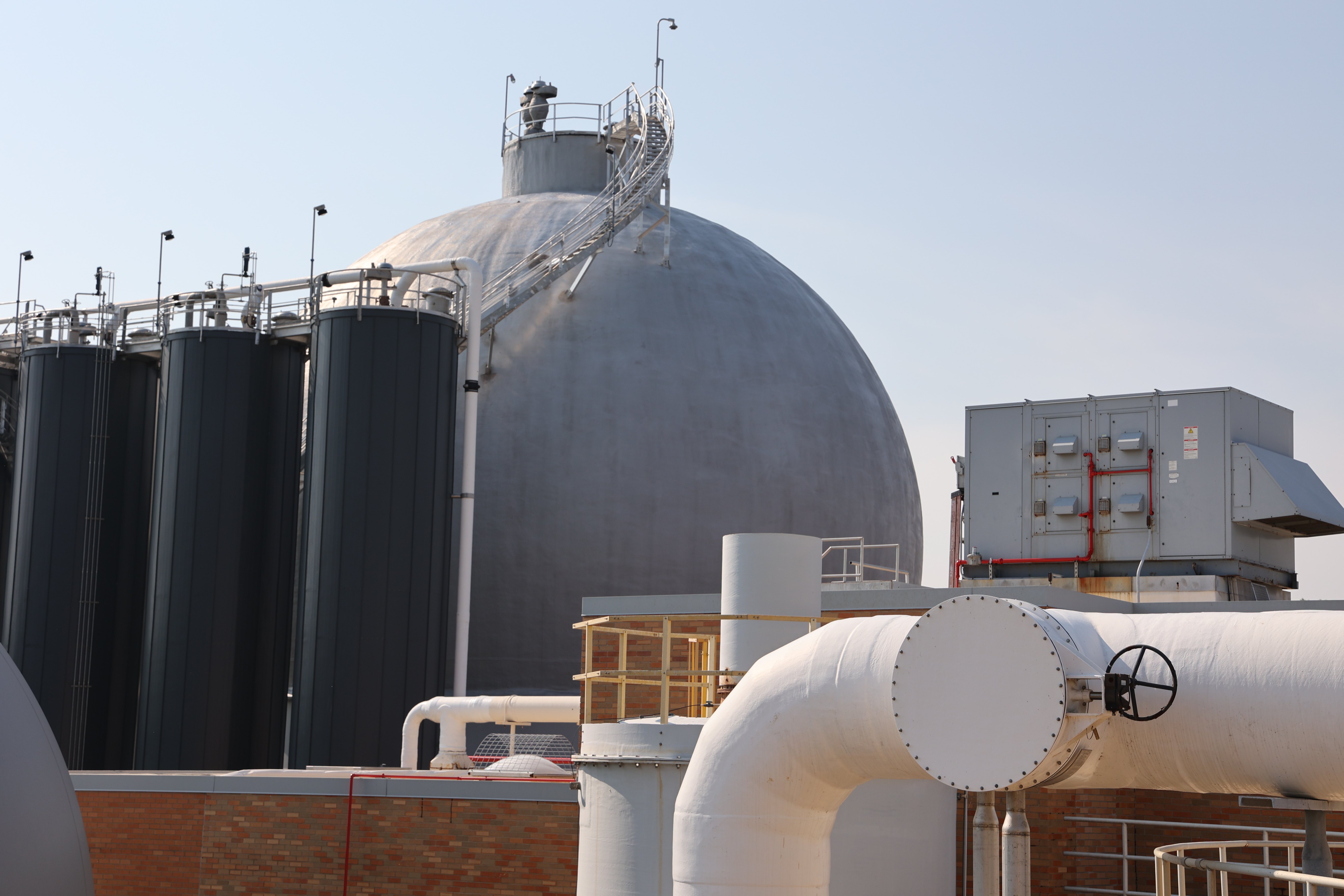 Large metal power plant stacks with yellow railings.