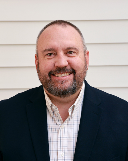 male executive wearing a black jacket with a white plaid button down